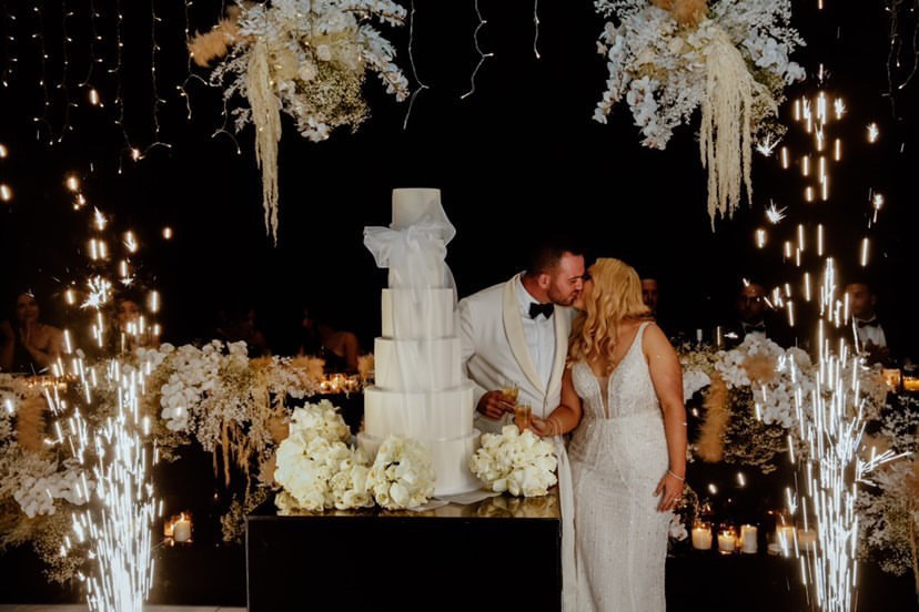 wedding cake cutting with fire works and the bride and groom 