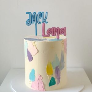 Buttercream cake with sharp edges and a smooth finish with paint brush strokes finished off with two name toppers.